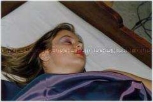 Geschminktes Mädchen liegt mit geschlossenen Augen im Bett (Sonderthema: Traum-Bilder)