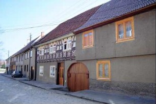 Häuserzeile mit traufständigen Häusern, darin denkmalgeschütztes Fachwerkhaus des vorigen Bildes