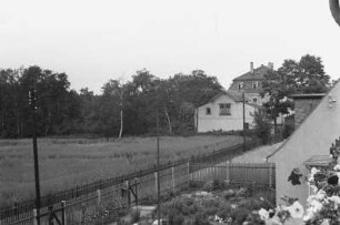 Feld : Blick über ein Feld in Richtung des Waldrandes; daneben ein großes Haus