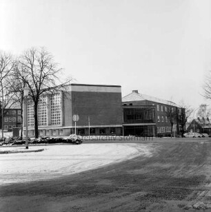 Erweiterungsbau [später Gebäude C] mit Kreistagssitzungssaal: vor Fertigstellung: vorn Busbahnhof und Mommsenstraße: hinten rechts Reimer-Hansen-Straße: links Bäume: dahinter Hauptgebäude [später Gebäude A]: Winter