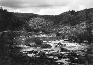 Flusslandschaft : Eine Flusslandschaft in Brasilien. Im Hintergrund bewaldete Hänge, im Vordergrund Steine und Felsen im Flussbett.