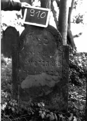 Grabstein 910 (Index: 100103775) Material: Sandstein Zustand: stark verwittert Maße HxBxT: 106x58x8 cm Beschreibung: Stele, eingezogener Rundbogenabschluss, Schriftfeld mit Konvexbogenabschluss, durch umlaufende Rille abgeteilt: Grabstein 910