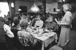 Hausfrauenbund Reinfeld: Gasthof, Saal: Jahresversammlung: rechts stehend Vorsitzende Thea Basse: links Damen an gedeckten Tischen: 31. März 1989