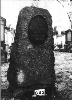 Grabstein 843 (Index: 99630345) Material: Granit mit geschliffener Platte Zustand: gut Maße HxBxT: 135x68x30 cm Beschreibung: grob stelenhaft behauener Stein mit ovaler Schriftplatte: Grabstein 843