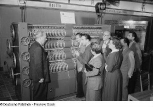 Besucher der Leipziger Herbstmesse 1954 betrachten ein Exponat der Vereinigung Volkseigener Betriebe des Elektromaschinenbaus (VEM)
