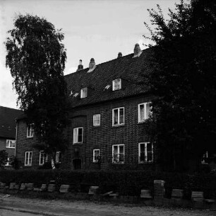 Hebbelstraße: Ausbau: vorn unbefestigte Straße, Stapel mit Gehwegplatten und Mülleimer: dahinter Wohnhäuser der Gemeinnützigen Baugenossenschaft Bad Oldesloe mit Vorgärten