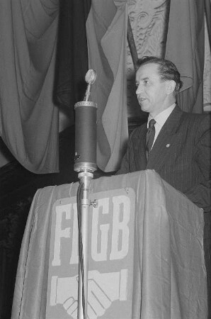 Redner auf dem Podium einer Veranstaltung, am Rednerpult die Fahne des Freien Deutschen Gewerkschaftsbundes (FDGB)