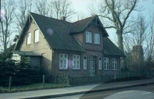 Allee 1: traufständiges Wohnhaus aus Backstein: Straßenfront mit Zwerchhaus, Eingangstür, Sprossenfenstern: links Giebelseite mit Wintergarten: hinten links rückwärtiger Querbau: vorne Jägerzaun