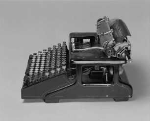 Typenhebelschreibmaschine "Smith Premier" (Modell 10). Vorderanschlag (sofort sichtbare Schrift), Volltastatur mit 84 Tasten, Farbband (Rollen hinten). Seitenansicht von rechts oben