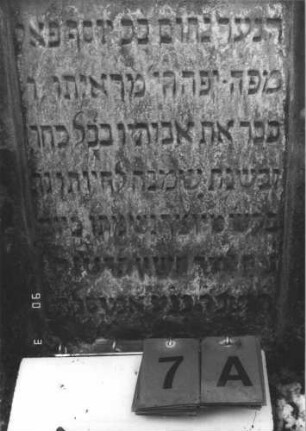 Grabstein 7 (Index: 99608691) Material: Sandstein Zustand: leicht verwittert Maße HxBxT: 77x50x10 cm Beschreibung: Stele mit flachem Spitzgiebel, vertiefter Textteil in gleicher Form Besonderheit: Kindergrab: Grabstein 7A