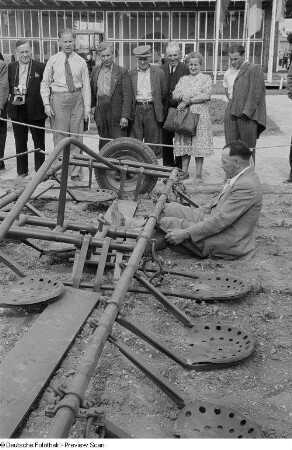 Ausstellungsbesucher während der Vorführung eines landwirtschaftlichen Gerätes