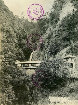 Honshū. Nunobiki-Wasserfall bei Kobe mit überdachter Brücke und Gebäuden beiderseits der Schlucht