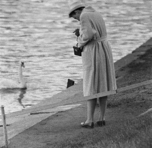Eine Frau fotografiert einen Schwan am Rand einer Talsperre