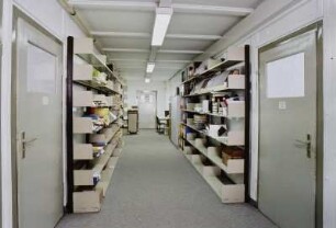 Sächsische Landesbibliothek - Staats- und Universitätsbibliothek Dresden. Zweigbibliothek Wirtschaftswissenschaften. Baracke 19/20. Gang der Baracke 19 mit Regalen im Dienstbereich