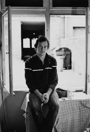Der Schauspieler Holm Gärtner vom Theater der Freundschaft Berlin vor geöffnetem Fenster auf einem Tisch sitzend, aufgenommen in Berlin