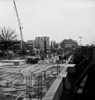 Bahnhofstraße: Parkhaus "Alter Lokschuppen": in Bau: Fundamente mit Baustahl-Armierungen: Baukran, Baufahrzeuge, Arbeiter, Bauwagen, Baumaterialien: rechts Bauzaun zum Bahnsteig hin: hinten rechts Bahnhofsgebäude, hinten Bildmitte Hochhaus Stormarnstraße / Ecke Bahnhofstraße: links Wohnblocks