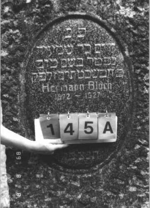 Grabstein 145 (Index: 99799432) Material: Granit Zustand: gut Maße HxBxT: 130x62x17 cm Beschreibung: Stele, grob behauen, Segmentbogenabschluß, Schriftfeld oval eingetieft, Sockel: Grabstein 145A