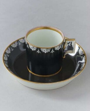 Tasse mit Unterteller mit Blütenrosetten auf schwarzem Grund