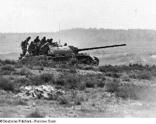 Deutschland . Nationale Volksarmee - Landstreitkräfte. Kampfpanzer mit aufgesessenen Schützen in Fahrt in offenem Gelände