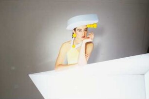 Model in Schaumstoffmode : Model mit Schaumstoffhut und -kostüm hinter einem Neonleuchtkörper