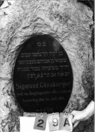 Grabstein 29 (Index: 99792476) Material: Kalkstein, Granitplatte Zustand: gut Maße HxBxT: 145x68x50 cm Beschreibung: grob stelenhaft behauener Stein, ovale Schriftplatte: Grabstein 29A