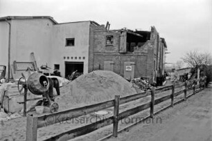 Bauernhof Hans Bartels: Wohnungsbau: Umbau eines Wirtschaftsgebäudes: stillgelegte Baustelle: davor Baumaterial, Mörtelmischer, Ziegelstapel, Sandhaufen: rechts Inhaber: vorn Zaun