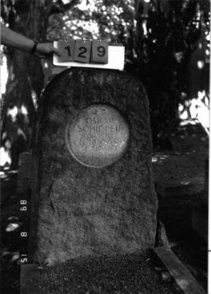 Grabstein 129 (Index: 100105325) Material: Granit Zustand: leicht verwittert Maße HxBxT: 103x58x20 cm Beschreibung: grob stelenhaft behauener Stein, rundes Schriftfeld eingetieft: Grabstein 129