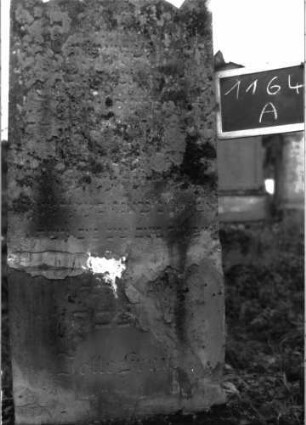 Grabstein 1164 (Index: 100104292) Material: Sandstein Zustand: stark verwittert mit fast vollständigem Textverlust, außerdem starke Zerstörungs- / Reparaturspuren Maße HxBxT: 156x53x15 cm Beschreibung: aufgesockelte Stele mit Dreiecksabschluss, Ecken zu Akroterien hochgezogen, Sockel felsartig gearbeitet, Stele war durchgebrochen: Grabstein 1164A