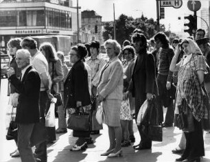Als auffälligstes öffentliches Verkehrsmittel gelten in den 1970-ger Jahren Busse, die wie PKW's auch in den Berufszeiten hoffnungslos stecken bleiben und eine rechtzeitige Ankunft am Arbeitsplatz wie Wohnung in Frage stellen. : Wartende Fahrgäste an einer Bushaltestelle.