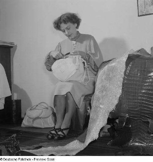 Frau mit einer Handtasche, daneben liegend verschiedene Lederarten (z.B. Schlangenleder)