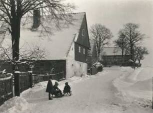 Verschneite Dorfstraße mit schlittenfahrenden Kindern (in Seiffen-Heidelberg oder in Ullersdorf bei Dresden)