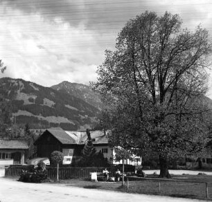Allgäu. Straßenbild mit Frauen, auf Parkbänken sitzend (vielleicht in Hindelang)