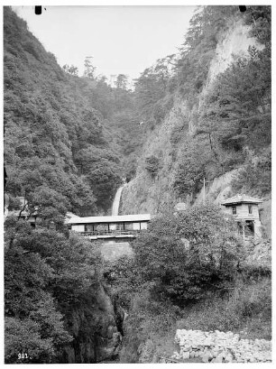 Honshū. Nunobiki-Wasserfall bei Kobe mit überdachter Brücke und Gebäuden beiderseits der Schlucht