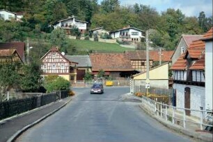 Dorfstraße Richtung Neustadt, an der Straße alte Häuser und Höfe, darüber am Hang DDR-Einfamilienhäuser