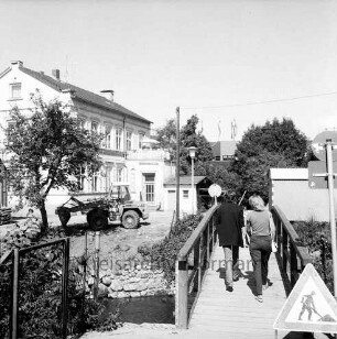 Heiligengeiststraße: Personen auf der Brücke über den Stadtarm der Trave zwischen Heiligengeiststraße und dem "Weg am alten Friedhof", vorne rechts ein Gefahrenzeichen Baustelle, links ein Gebäude der Heiligengeiststraße, im Hintergrund ein Kaufhausgebäude, Blick nach Nordosten