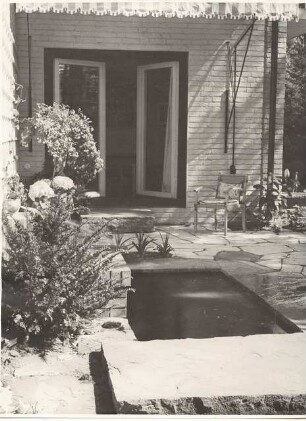 Garten Dr. Bolle, Berlin-Dahlem. Umbau: Terrasse mit Plattenverlegung am Wasserbecken, Gartenstuhl