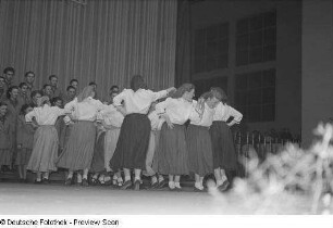 Tanzende junge Frauen bei einer Kulturveranstaltung in Halle II, im Hintergrund ein Chor
