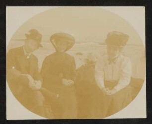 Ein unbekannter Herr mit bayerischem Gamsbart am Hut und zwei Damen am Meer