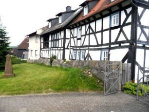 Treis an der Lumda-Evangelische Kirche - Kirchhof im Nordnordwesten mit Kirchhofmauer (Wehrgang mit Steinbrüstung sowie Schießscharten abgetragen) mit außenseitig angebauten (neuzeitlichen) Fachwerkhäusern