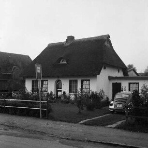 Polizeidienststelle Bargfeld-Stegen: Mittelweg: Reetdachkate mit Vorgarten: links davor Hinweisschild: rechts Auffahrt mit Polizei-VW-Käfer: hinten links Scheune
