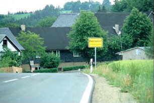Ortseingang, abschüssige Straße, erste Häuser