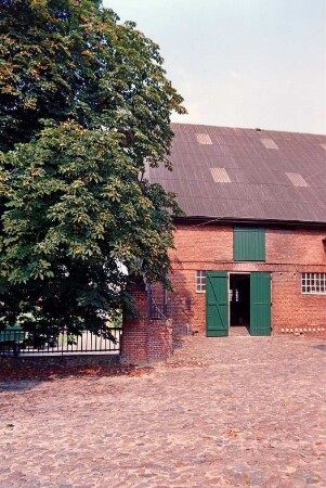 Fritz-Berodt-Straße 7-9: Hofanlage: westliches Wirtschaftsgebäude, Traufseite, Teilansicht: Tor, darüber Luke: davor Hofplatz mit Kopfsteinpflaster, Hofmauer mit Geländer, Pfeiler: Baum: 19. August 1993