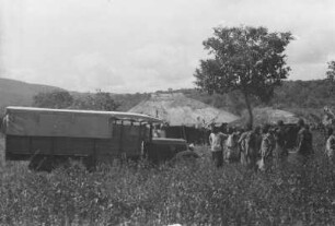Duka mit Zuschauern : Expeditionsautomobil in einem Dorf mit einer Gruppe von Dorfbewohnern.