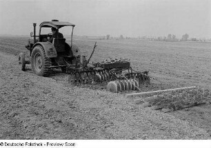Bauer mit Traktor beim Pflügen eines Feldes