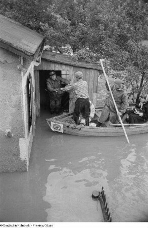 Herausreichen von Gegenständen aus einem überschwemmten Haus in ein Rettungsboot