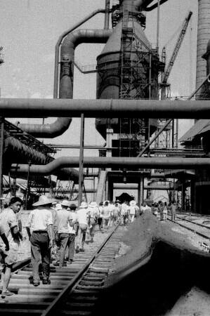 Wuhan (China). Stahlwerk mit Werkbahngleisen, dort Arbeiterkolonne