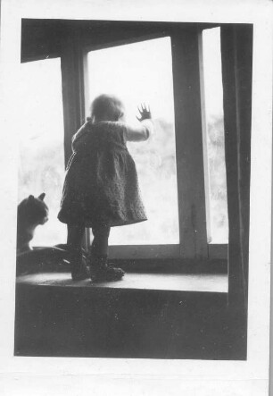 Kleines Mädchen mit Katze am Fenster