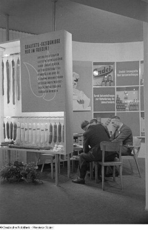 Handelsvertreter an einem Messestand mit Fleisch- und Wurstwaren