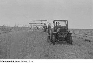 Landwirte beim Mähen von Getreide mit Hilfe eines Traktors und einer Mähmaschine