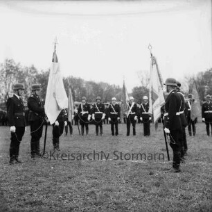 Meddewade: Freiwillige Feuerwehr Meddewade: Fahnenweihe: Festwiese: Fahnenträger mit der eingepackten Meddewader Fahne und der Weihfahne des Amtes Bad Oldesloe-Land: dahinter Fahnenträger benachbarter Wehren: hinten angetretene Wehren und Zuschauer: 01.06.1974